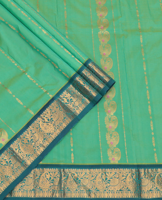 Green Art Silk Pavadai Material Set, Delicately Woven with Zari Designs on Its Skirt, Complemented by a Contrast Paisley Zari Border, and a Matching Blouse