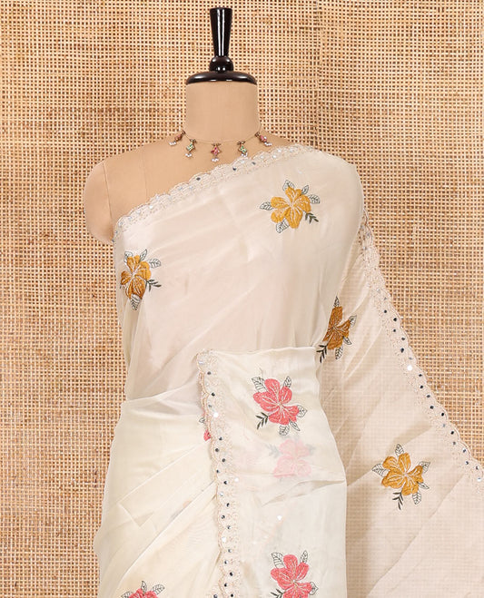 Cream floral motifs embroidered rangoli chiffon saree with mirror work border, embroidered pallu, and a contrast intricate scallop design embroidered blouse