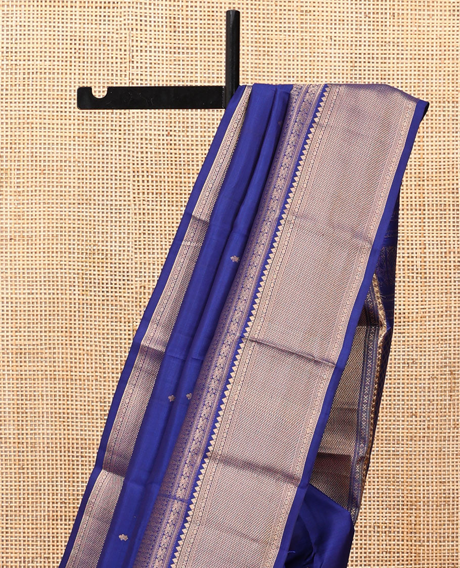Blue Vasundhara Silk Saree Gleamed with Zari Buttas All Over Its Body, Highlighted with a Zari Border of Thilakam Mokku, Muthu, Cross Kamalam, and Mayil Kann Designs, Grand Pallu of Jaal Design, and Paired with a Matching Blouse