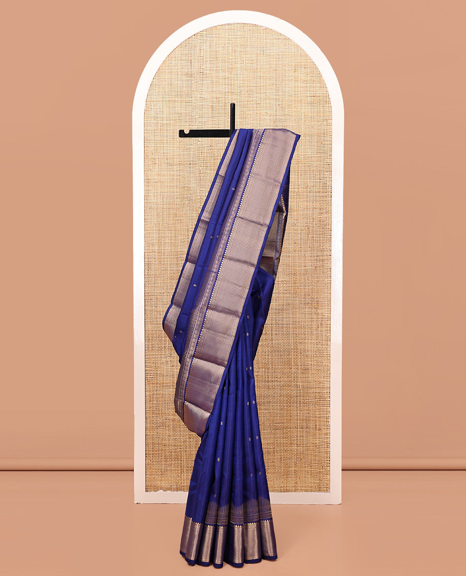 Blue Vasundhara Silk Saree Gleamed with Zari Buttas All Over Its Body, Highlighted with a Zari Border of Thilakam Mokku, Muthu, Cross Kamalam, and Mayil Kann Designs, Grand Pallu of Jaal Design, and Paired with a Matching Blouse