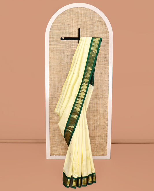 Pale Yellow Kanchipuram Silk Saree, Subtly Sparkled with Zari Buttas All Over Its Body, Complemented by a Contrast One-Sided Korvai Border of Thilakam Mokku, Banaras, and Jaal Designs, Pallu of Zari Designs, and Comes Without a Blouse