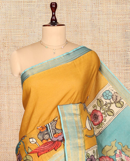 Gold Kalamkari Silk Saree, Impeccably Styled with Floral Vine and Human Motifs Print, a Contrast Traditional Zari Border, Pallu Features Peacocks, and a Contrast Blouse