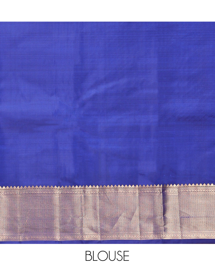 Blue Vasundhara Silk Saree Gleamed with Zari Buttas All Over Its Body, Highlighted with a Zari Border of Thilakam Mokku, Muthu, Cross Kamalam, and Mayil Kann Designs, Grand Pallu of Jaal Design, and Paired with a Matching Blouse