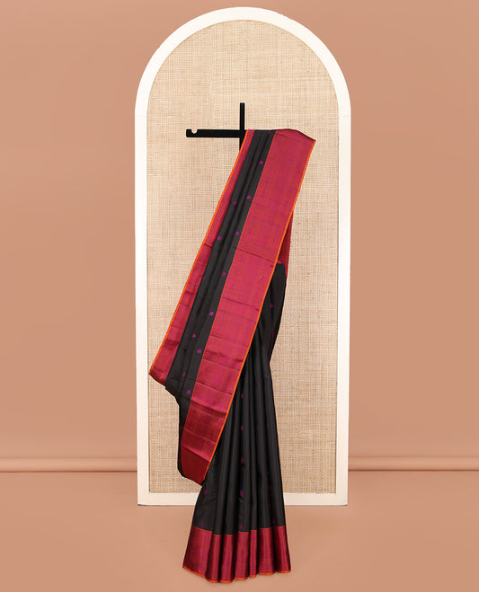 Black Kanchipuram Silk Saree, Masterfully Woven with Mayil-Chakram Buttas All Over Its Body, Complemented by a Contrast Border of Thilakam Mokku, Iruthalai Pakshi, and Kuyil Kann Designs, and Pallu of Jaal Designs, and Paired with a Contrast Blouse