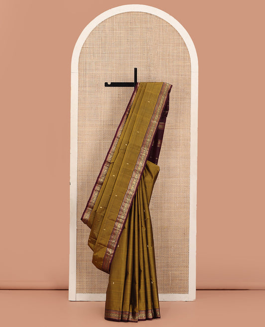 Mustard Kanchipuram Silk Saree Adorned with Vazhaipoo Stripes and Zari Buttas, Complemented by a Contrast Border of Thazampoo Rekku, Greek Key, and Kodi Mayil Designs, Zari-Woven Pallu, and Paired with a Contrast Blouse