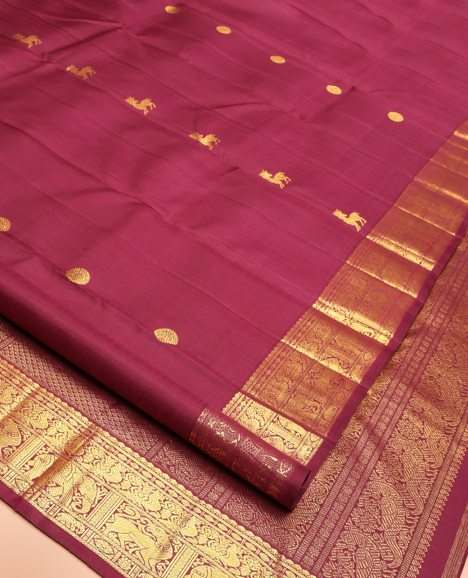 Red Kanchipuram Silk Saree, Lightly Embellished with Kuthirai and Chakram Buttas All Over Its Body, Highlighted by Zari Border of Salngai, Poun, Mayil, Yaali, and Yaanai Designs, Pallu of Ara Maadam Design, and Paired with a Matching Blouse