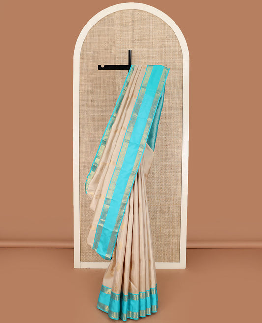 Cream manga buttas Kanchipuram silk saree, contrast rettai pettu border of kathir and annam chakram motifs, and butta enclosed checked pallu