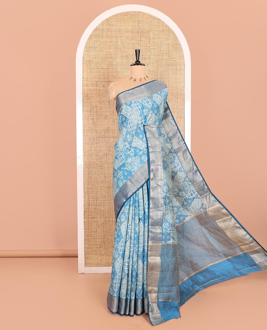 Blue Semi-Tussar Saree Meticulously Crafted with Floral-Enclosed Diamond Patterns Printed Across the Body, Featuring a Subtly Woven Border with Traditional Zari Designs, and a Pallu Elevated with Zari Stripes, Paired with a Matching Blouse