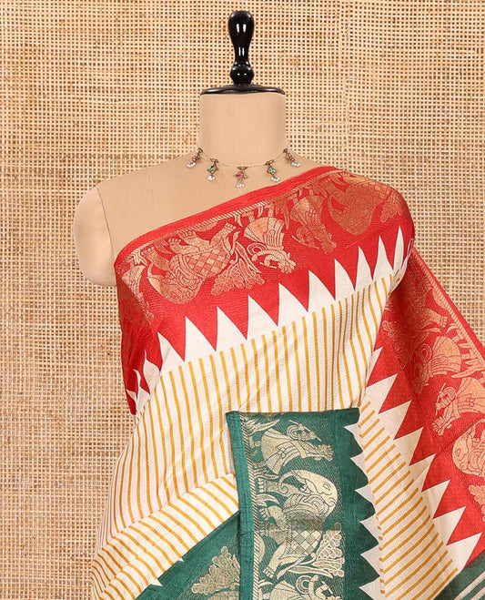 Chikku Base Dola Silk Saree Subtly Sparkled with Yellow Stripes All Over Its Body, Complemented by a Contrast Ganga-Jamuna Border of Human Figurines and Elephant Motifs, Pallu of Floral-Paisley Print, and Paired with a Contrast Blouse