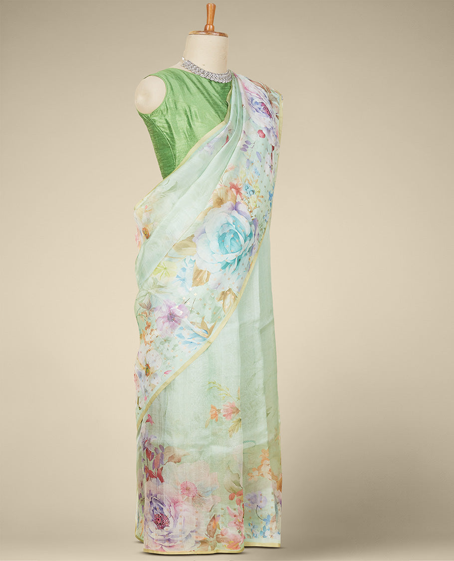 Borderless pastel green organza saree features kaleidoscopic-colored floral motifs print