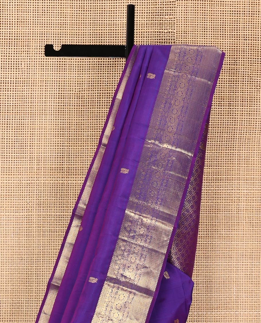 Violet Kanchipuram Silk Saree, Ornamented with Zari Buttas All Over Its Body, Highlighted by Zari Border of Thilakam, Mayil Kann, Poun, Jada Nagam, Dhavana Kodi, and Mayil Kann Designs, Pallu of Jaal Designs, and Paired with a Matching Blouse