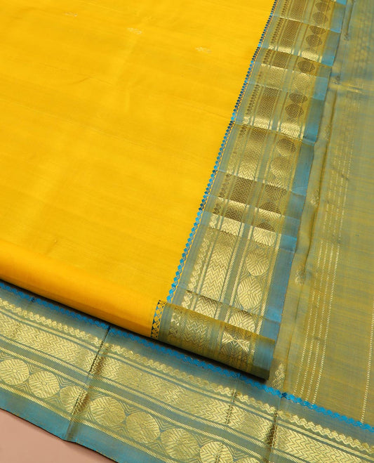 Yellow Kanchipuram Silk Saree Subtly Sparkled with Zari Buttas All Over Its Body, Complemented by a Contrast One-Sided Border of Thilakam Mokku, Banaras, Vanki, and Rudraksham Designs, Pallu of Zari Motifs, and Comes Without a Blouse
