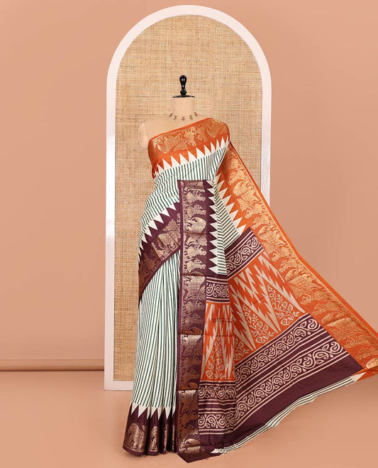 Chikku Base Dola Silk Saree Subtly Sparkled with Green Stripes All Over Its Body, Complemented by a Contrast Ganga-Jamuna Border of Human Figurines and Elephant Motifs, Pallu of Floral-Paisley Print, and Paired with a Contrast Blouse