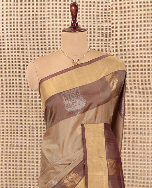 Light Sandal Uppada Silk Saree Highlighted with Paisley Buttas All Over Its Body, Complemented by Contrast Border of Temple and Chariot Designs, Grandly Woven Pallu of Temple Floral Vine Designs, and Paired with a Contrast Blouse