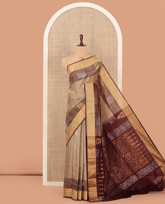 Light Sandal Uppada Silk Saree Highlighted with Paisley Buttas All Over Its Body, Complemented by Contrast Border of Temple and Chariot Designs, Grandly Woven Pallu of Temple Floral Vine Designs, and Paired with a Contrast Blouse