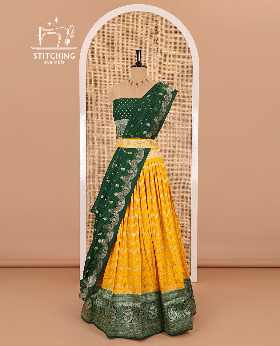 Haldi yellow chiniya crepe half-saree, chevron zari jacquard with contrast intricate patterned stone work bordered skirt, contrast blouse, and a scallop bordered intricate dhavani
