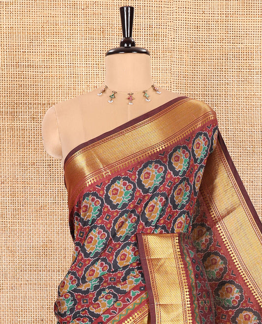 Black Patola Saree Adorned with Ikkat-Style Buttas Enclosed Round Design, Complemented by a Contrast Traditional Zari Design Border, Featuring Intricate Ikkat Style Pallu, and Paired with a Contrast Blouse