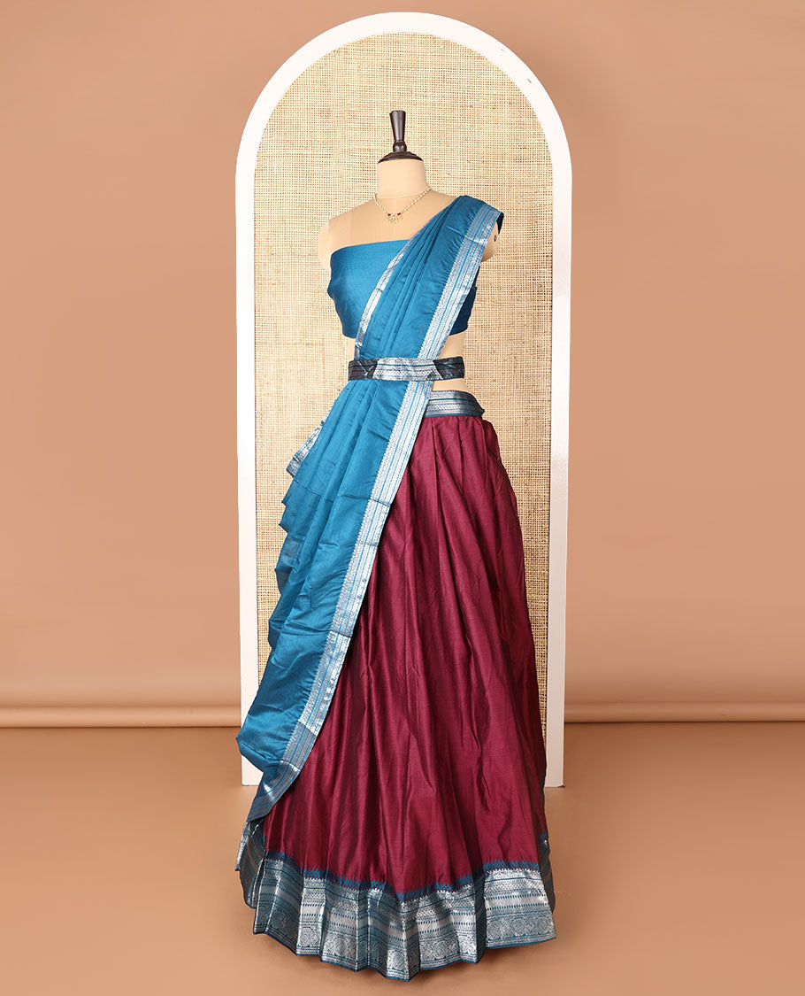 Maroon art-silk half-saree, plain with contrast temple traditional design bordered skirt, a contrast blouse, and a plain zari bordered dhavani
