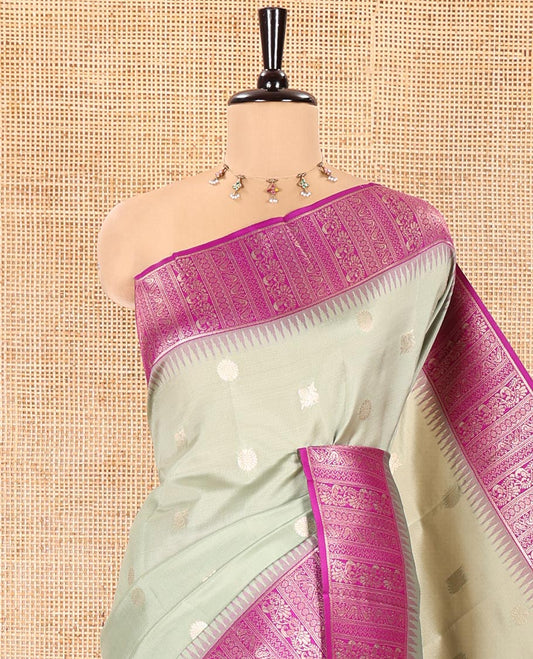 Green Kanchi Silk Saree, Featuring Peacock-Chakram Buttas All Over Its Body, Complemented by a Contrast Border of Floral Creeper Designs, an Intricately Designed Pallu, and Paired with a Matching Blouse