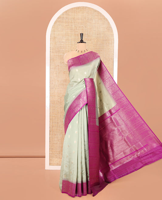 Green Kanchi Silk Saree, Featuring Peacock-Chakram Buttas All Over Its Body, Complemented by a Contrast Border of Floral Creeper Designs, an Intricately Designed Pallu, and Paired with a Matching Blouse