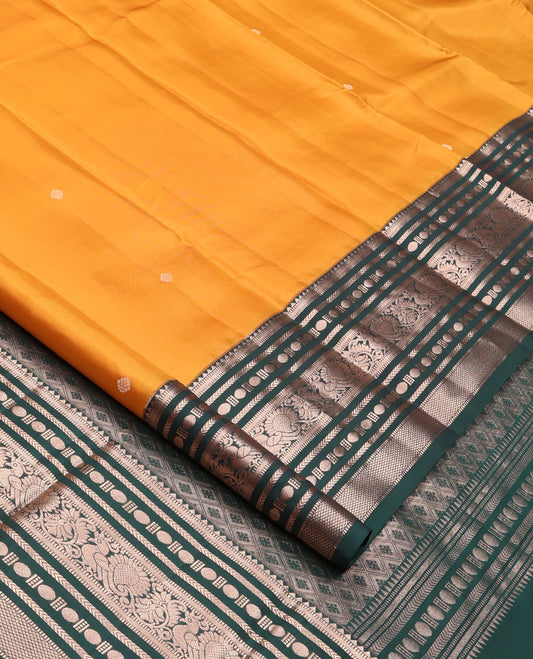 Yellow Vasundhara Silk Saree, Prettified with Zari Buttas All Over Its Body, Complemented by Contrast Border of Rekku, Muthu, Kathir, Poun, Mayil, and Mayil Kann Designs, Grand Jaal Pallu and Paired with a Contrast Blouse