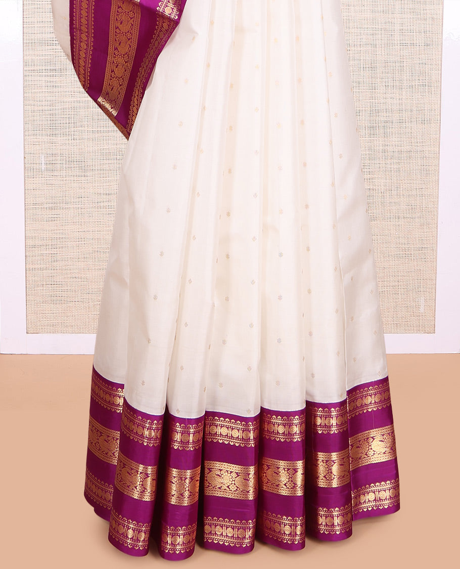 White Vasundhara Silk Saree Elegantly Embellished with Zari Buttas, Complemented by a Varisai Pettu Border Featuring Rekku, Muthu, Banaras, Rudraksham, and Mayil Designs, Majestically Woven with a Zari-Designed Pallu, and Paired with a Contrast Blouse