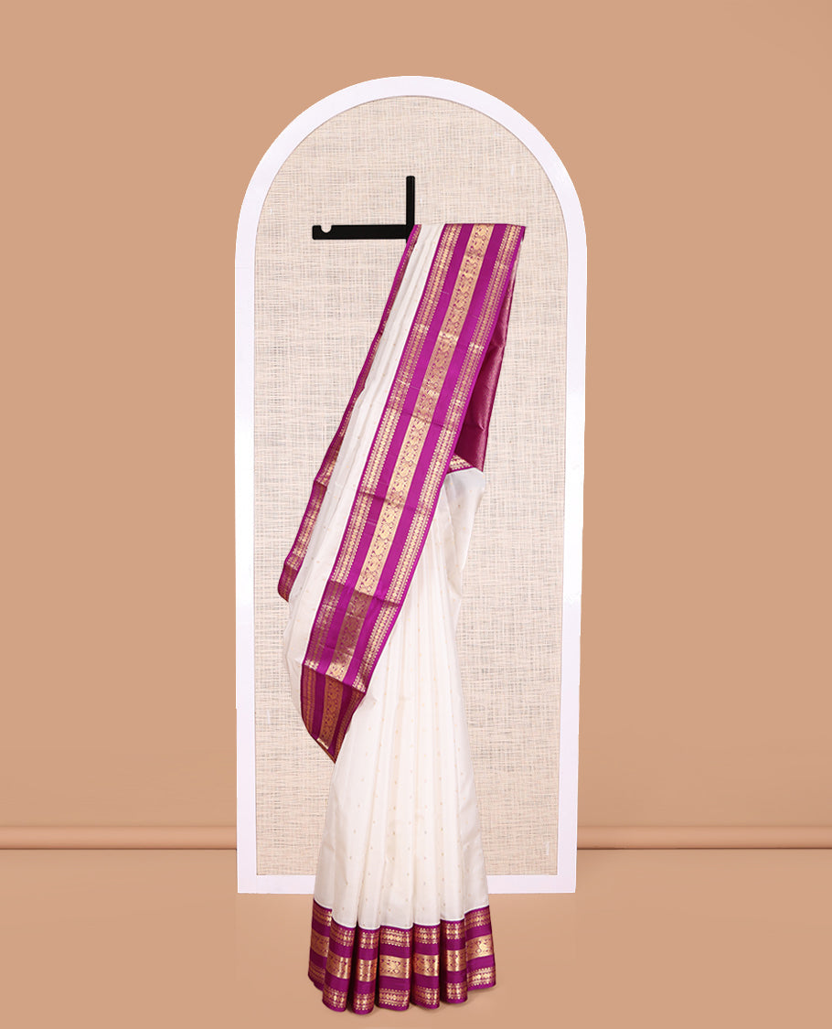 White Vasundhara Silk Saree Elegantly Embellished with Zari Buttas, Complemented by a Varisai Pettu Border Featuring Rekku, Muthu, Banaras, Rudraksham, and Mayil Designs, Majestically Woven with a Zari-Designed Pallu, and Paired with a Contrast Blouse