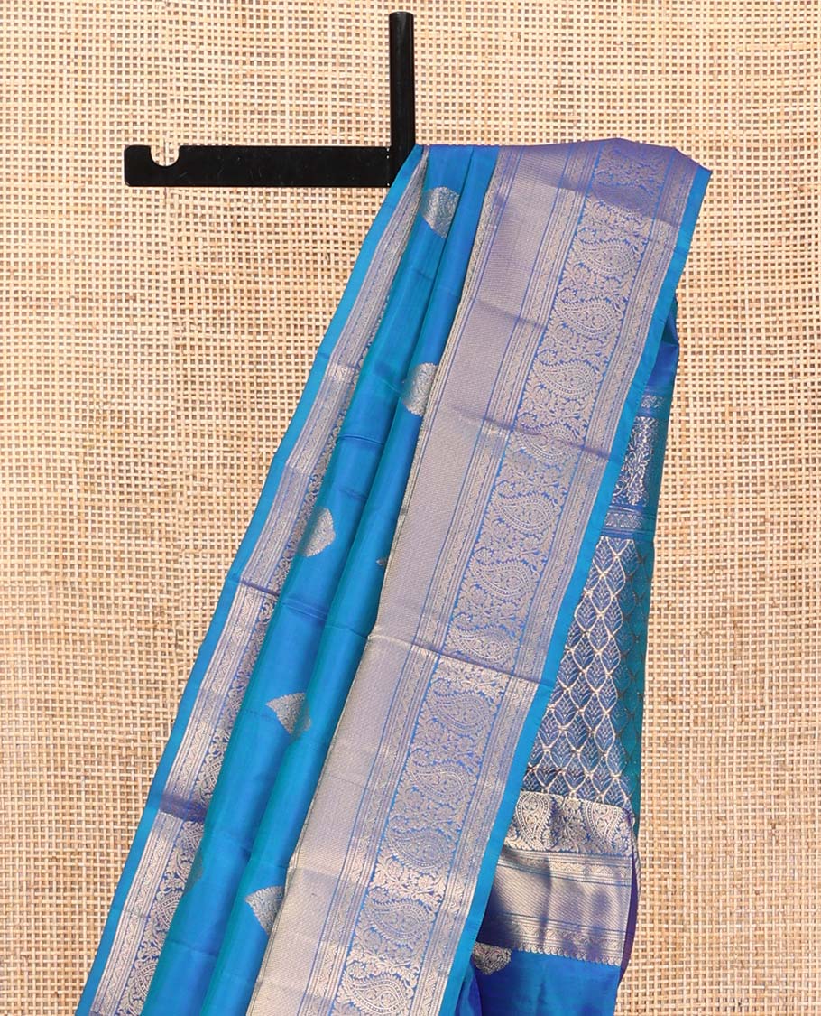Blue Vasundhara Silk Saree, Mesmerized with Zari Buttas on Its Body, Highlighted by a Zari Border of Manga Mokku, Muthu, and Arumbu Manga Designs, Pallu Steeped with Leaf Designs, and Paired with a Matching Blouse