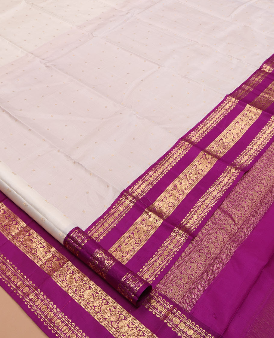 White Vasundhara Silk Saree Elegantly Embellished with Zari Buttas, Complemented by a Varisai Pettu Border Featuring Rekku, Muthu, Banaras, Rudraksham, and Mayil Designs, Majestically Woven with a Zari-Designed Pallu, and Paired with a Contrast Blouse