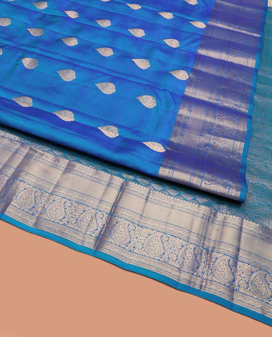 Blue Vasundhara Silk Saree, Mesmerized with Zari Buttas on Its Body, Highlighted by a Zari Border of Manga Mokku, Muthu, and Arumbu Manga Designs, Pallu Steeped with Leaf Designs, and Paired with a Matching Blouse