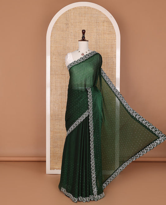 Deep forest green designer saree features gleaming crystal stone embedded all-over its body, scallop leaf motifs embroidered border