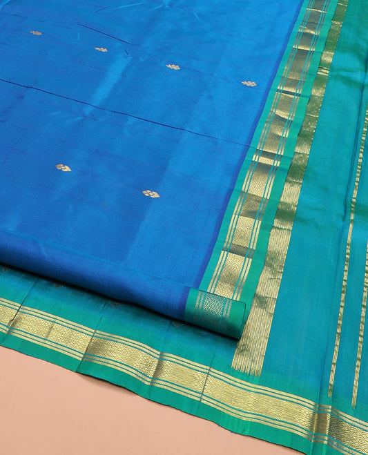Blue Kanchipuram Silk Saree Elegantly Designed with Zari Buttas All Over Its Body, Complemented by a Contrast One-Sided Border of Banaras, and Mayil Kann Designs, Pallu of Zari Motifs, and Comes Without a Blouse