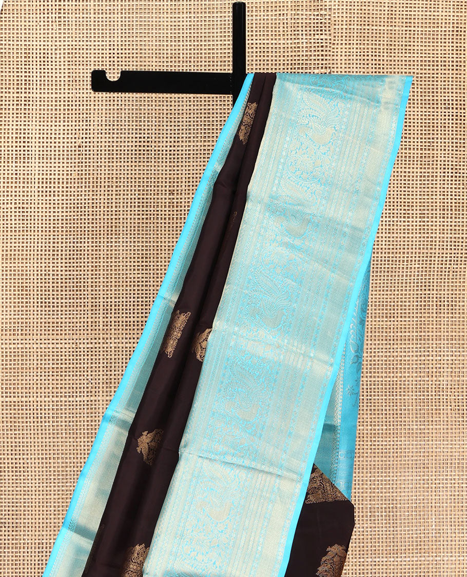 Brown Vasundhara Silk Saree, Elegantly Highlighted with Zari Buttas All Over Its Body, Complemented by Contrast Border of Salngai, Rettai Neli, Kodi Mayil, and Mayil Kann Designs, Grandly Embellished Pallu, and Paired with a Contrast Blouse