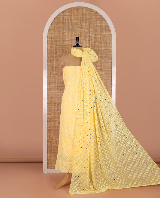 Yellow material chudidar set, paisleys and jaal schiffli sequins embroidered mul georgette top, a matching bottom, and a mirror work dupatta