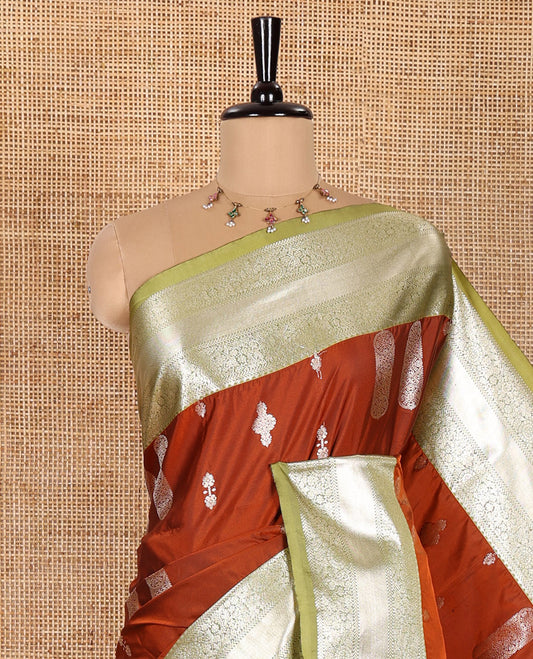 Rust Orange Elite Soft Silk Saree Enriched with Zari Buttas All Over Its Body, Complemented by Contrast Floral Creeper Zari Border, Scintillating Pallu of Intricate Designs, and Paired with a Contrast Blouse