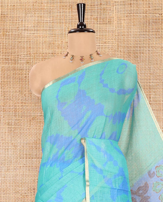 Rama Green Linen Cotton Saree, Elevated with Shibori Printed on Its Body, Subtle Piping Border, Pallu Features Floral Print, and Paired with a Contrast Floral Printed Blouse