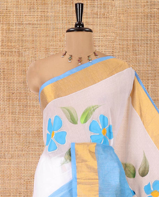 White and Blue Khadi Mul Cotton Saree, Adorned with Hand-Brush Painting-Style Floral Block Printed Body, a Subtle Gold Zari Border, a Self-Pallu, and Paired with a Matching Blouse