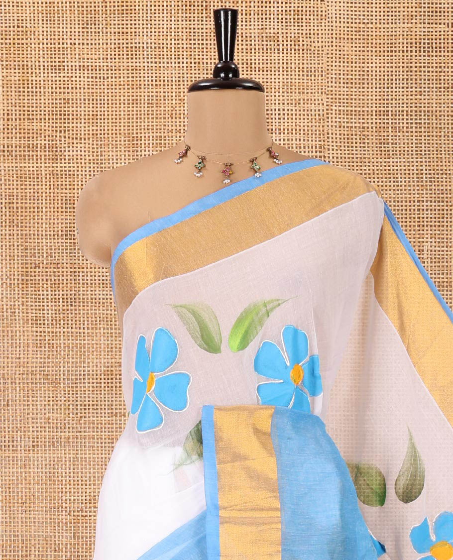 White and Blue Khadi Mul Cotton Saree, Adorned with Hand-Brush Painting-Style Floral Block Printed Body, a Subtle Gold Zari Border, a Self-Pallu, and Paired with a Matching Blouse