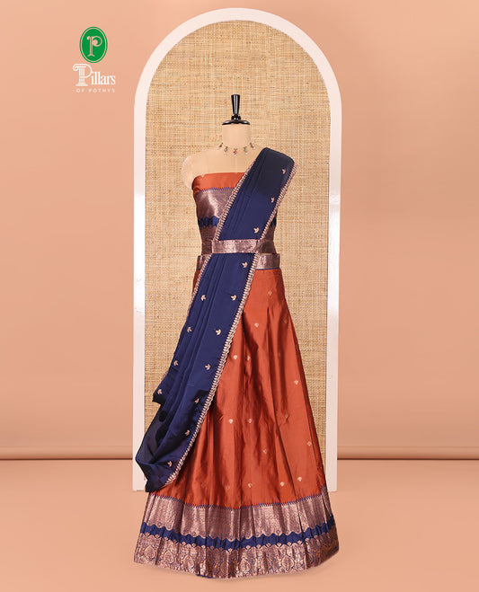 Rust-Navy Blue Semi-Banarasi Half-Saree Elevated with Zari Buttas on Its Skirt, Complemented by a Contrast Traditional Zari Temple Rettai Pettu Border, Paired with a Matching Blouse, and a Satin Georgette Embroidered Scallop Dhavani