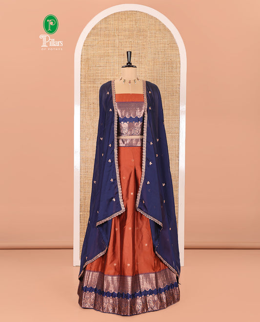 Rust-Navy Blue Semi-Banarasi Half-Saree Elevated with Zari Buttas on Its Skirt, Complemented by a Contrast Traditional Zari Temple Rettai Pettu Border, Paired with a Matching Blouse, and a Satin Georgette Embroidered Scallop Dhavani
