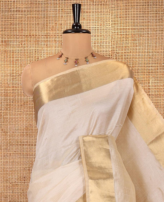 Cream Plain Art Tussar Saree, Highlighted by a Gleaming Golden Zari Bavanji Border, Pallu Steeped with Zari Stripes, and Paired with a Matching Blouse