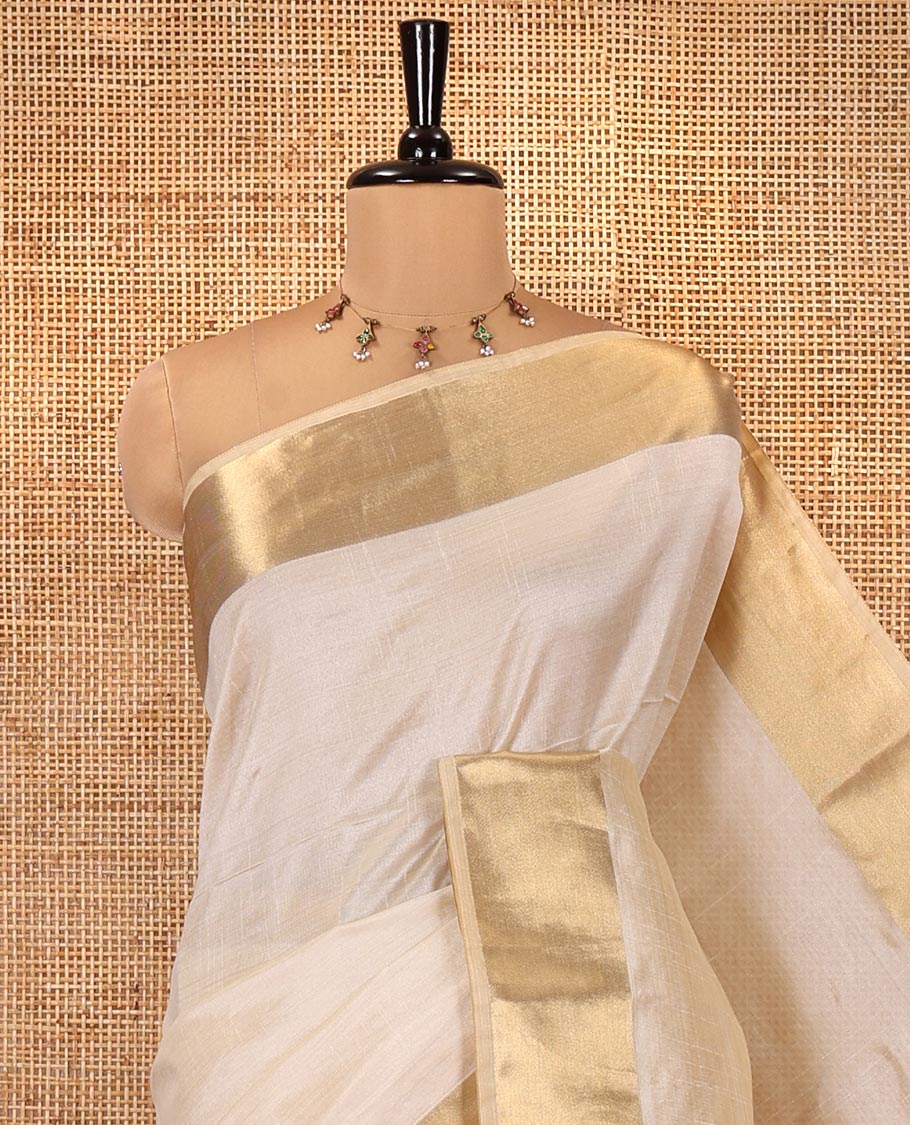 Cream Plain Art Tussar Saree, Highlighted by a Gleaming Golden Zari Bavanji Border, Pallu Steeped with Zari Stripes, and Paired with a Matching Blouse