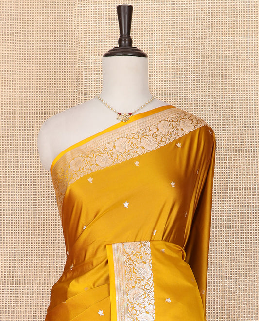 Yellow Semi-Banaras Satin Saree Subtly Sparkled with Zari Buttas, Self-Border Gleamed Up with Floral Creeper Designs, Pallu Creatively Woven of Lotus Motifs, and Paired with a Matching Blouse