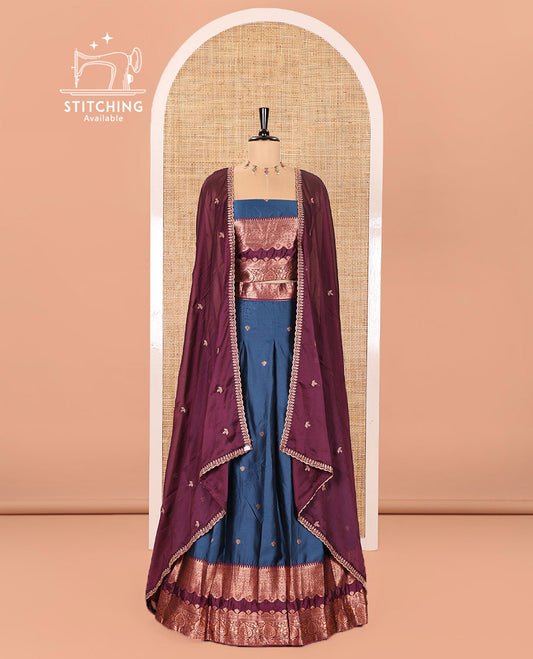 Blue-Purple Semi-Banarasi Half-Saree Enriched with Zari Buttas on Its Skirt, Complemented by a Contrast Traditional Zari Temple Rettai Pettu Border, Paired with a Matching Blouse, and a Satin Georgette Embroidered Scallop Dhavani