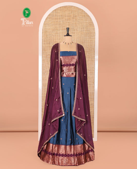 Blue-Purple Semi-Banarasi Half-Saree Enriched with Zari Buttas on Its Skirt, Complemented by a Contrast Traditional Zari Temple Rettai Pettu Border, Paired with a Matching Blouse, and a Satin Georgette Embroidered Scallop Dhavani