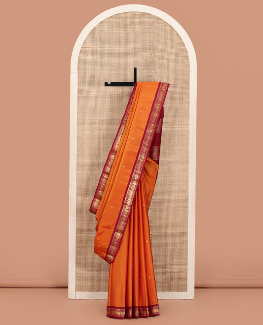 Orange Kanchipuram Silk Saree Prettified with Zari Buttas, Complemented by Contrasting Border of Thilakam Mokku, Muthu, Rudraksham, Mayil and Manga Designs, Pallu Mirroring the Same Border Design, and Paired with a Contrast Blouse