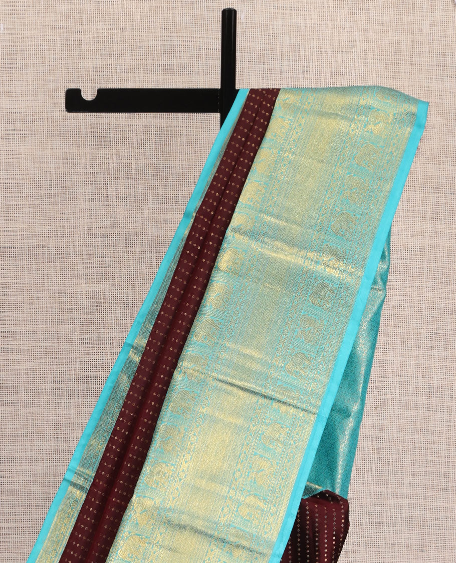Brown Vasundhara Silk Saree Delicately Woven with Zari Buttas, Highlighted with a Contrast Border of Cross Kamalam, Mayil, Banaras, Yaanai, and Mayil Kann Designs, Pallu Grandly Woven with Jaal Designs, and Paired with a Contrast Blouse