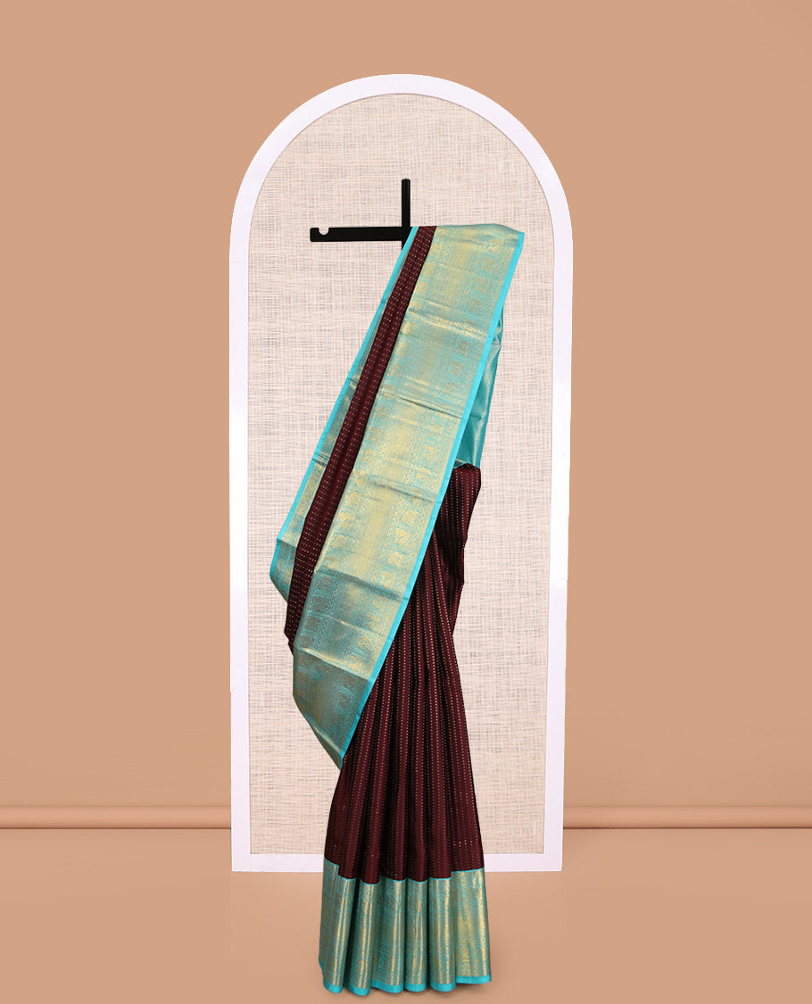 Brown Vasundhara Silk Saree Delicately Woven with Zari Buttas, Highlighted with a Contrast Border of Cross Kamalam, Mayil, Banaras, Yaanai, and Mayil Kann Designs, Pallu Grandly Woven with Jaal Designs, and Paired with a Contrast Blouse