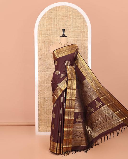 Coffee Brown Kanchipuram Budget Silk Saree Gleamed Up with Zari Buttas, Highlighted by Zari Border of Peacock Chakram Designs, Pallu Richly Detailed with Kolam and Chariot Designs, and Paired with a Matching Blouse