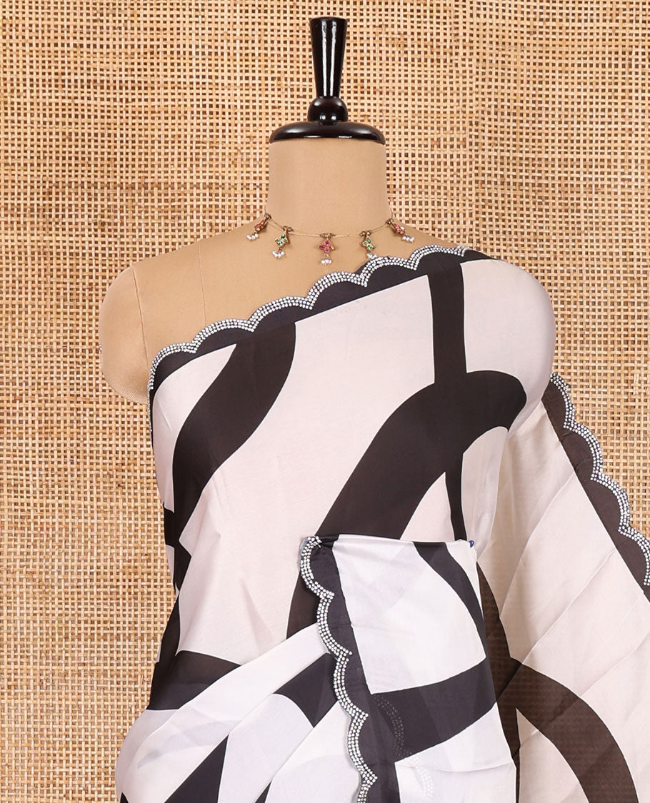 Cream and black abstract printed satin crepe saree, scallop jarkan stone work border, self-pallu, and a contrast printed blouse